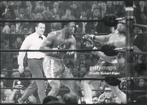 Joe Frazier hits Muhammad Ali with a left hook as referee Arthur Mercante looks on during the World Heavyweight Championship at Madison Square Garden...