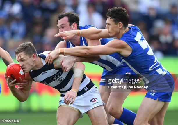 Joel Selwood of the Cats is tackled by Todd Goldstein and Ben Jacobs of the Kangaroos during the round 12 AFL match between the Geelong Cats and the...