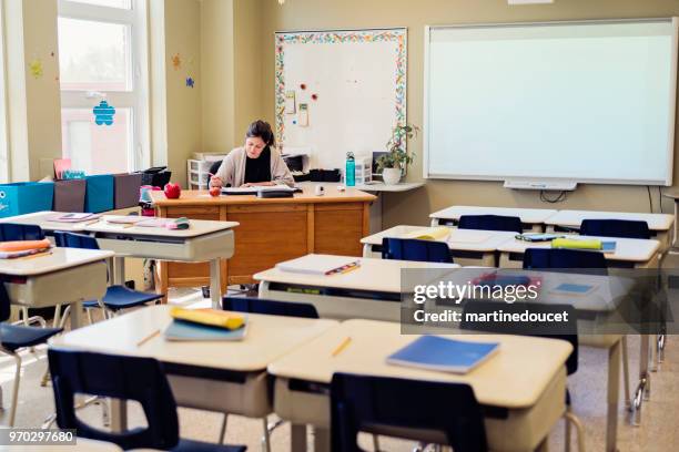 lehrer arbeiten an ihrem schreibtisch in leeren klassenzimmer. - interaktives whiteboard stock-fotos und bilder