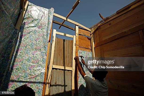 Pierre-Toussaint Glanys uses gift wrapping paper to wallpaper the inside of his shack where the collapsed Marche Tete Boeuf market once stood along...