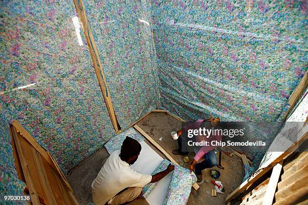 Pierre-Toussaint Glanys and Claudette Clement use gift wrapping paper to wallpaper the inside of the shack they have built where the collapsed Marche...