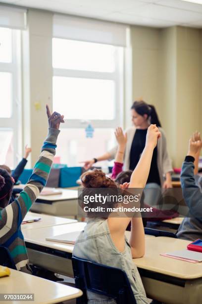 elementary school children with arms raised in classroom. - "martine doucet" or martinedoucet stock pictures, royalty-free photos & images