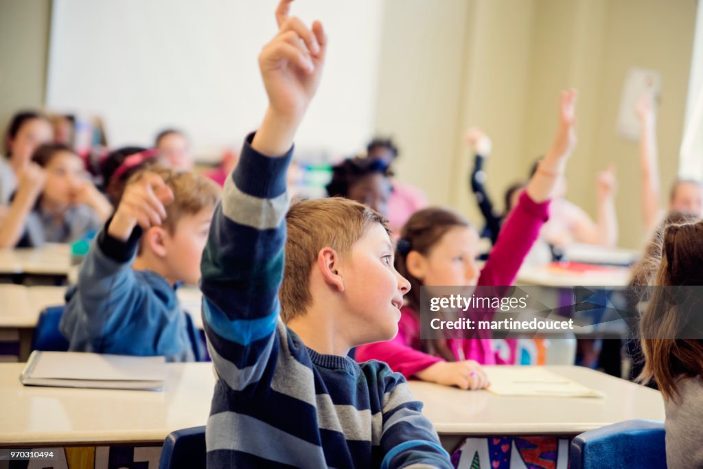 Folkskolan barn med armarna upp i klassrummet.