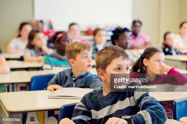 elementary school children sitting and listening in classroom. - "martine doucet" or martinedoucet stock pictures, royalty-free photos & images