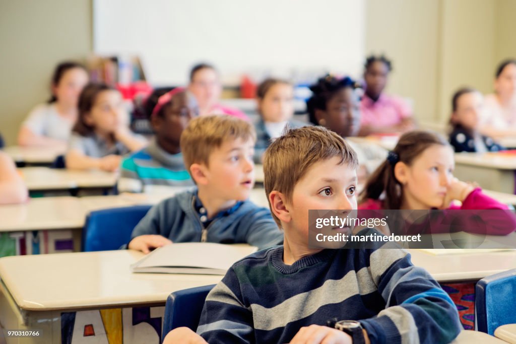 Crianças do ensino fundamental sentado e ouvindo na sala de aula.