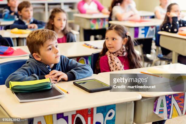 elementary school children sitting and listening in classroom. - "martine doucet" or martinedoucet stock pictures, royalty-free photos & images
