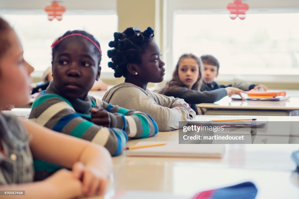 Escuela primaria los niños sentados y escuchar en el aula.