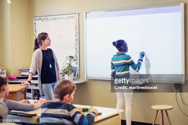 african-american girl writing on interactive whiteboard in classroom. - "martine doucet" or martinedoucet stock pictures, royalty-free photos & images