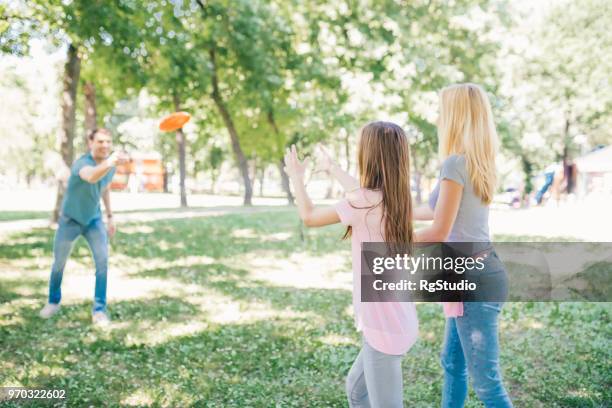 familia joven feliz jugando con la placa de plástico naranja en parque - plastic plate fotografías e imágenes de stock