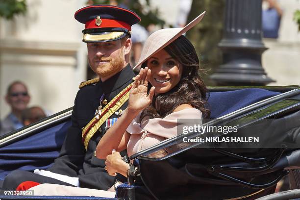 Britain's Prince Harry, Duke of Sussex and Britain's Meghan, Duchess of Sussex return in a horse-drawn carriage after attending the Queen's Birthday...