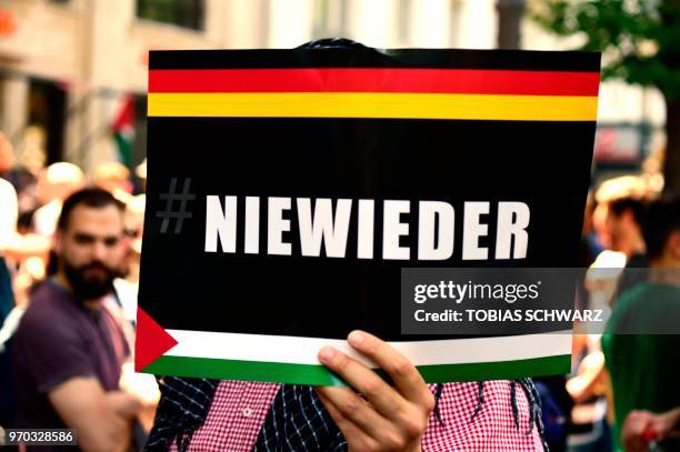 Protester holds a sign reading "Never again" during a Quds-day Demonstration on the occasion of the so-called "Al-Quds day" in Berlin, on June 9,...