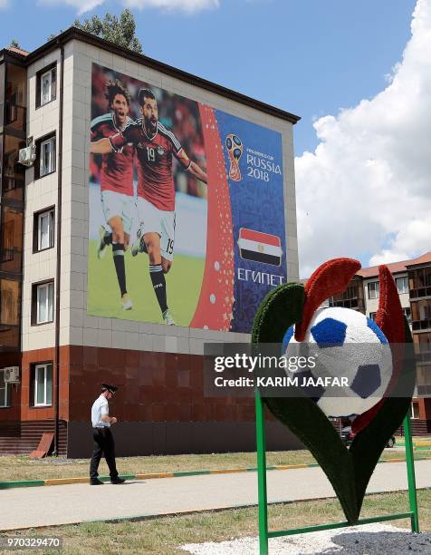 Police officer walks in front of a giant poster featuring Egypt's footballers Abdalla Said and Mohamed Elneny attached to the wall of a residential...