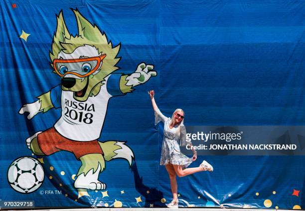 Woman poses for pictures in front of a banner featuring Zabivaka, the official mascot of the upcoming 2018 FIFA World Cup, outside Olymp Stadium,...