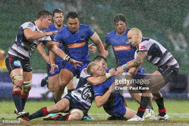Andrew Deegan of the Force gets tackled by Tayler Adams and Billy Meakes of the Rebels during the World Series Rugby match between the Force and the...