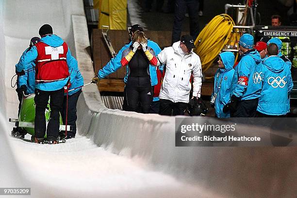 Cathleen Martini of Germany 2 is helped fom the track after they crashed out, team mate Romy Logsch of Germany fell from the back of the bobsleigh...