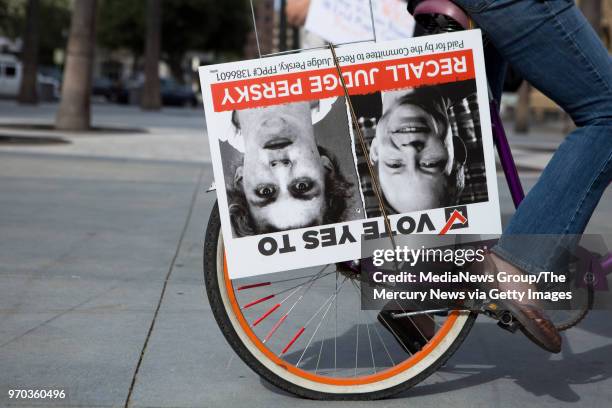 Adrienne Regard places a "Vote Yes to Recall Judge Persky" poster on the back wheel of her bike during a recall rally outside of attorney James...