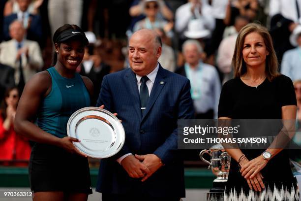 Second placed Sloane Stephens of the US poses with her trophy, next to French Tennis Federation President Bernard Giudicelli and former Spanish...