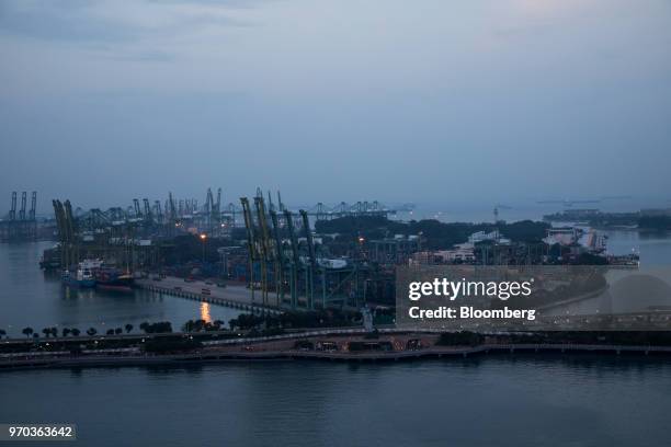 Stacked containers sit among gantry cranes illuminated at dusk at Tanjong Pagar Container Terminal, operated by PSA International Pte, at the Port of...