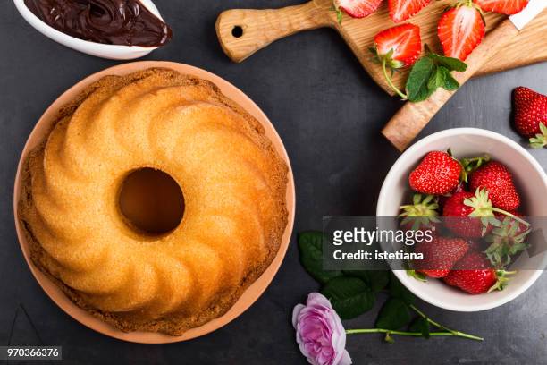 preparation bundt cake with chocolate ganache and fresh strawberries - cakes stockfoto's en -beelden