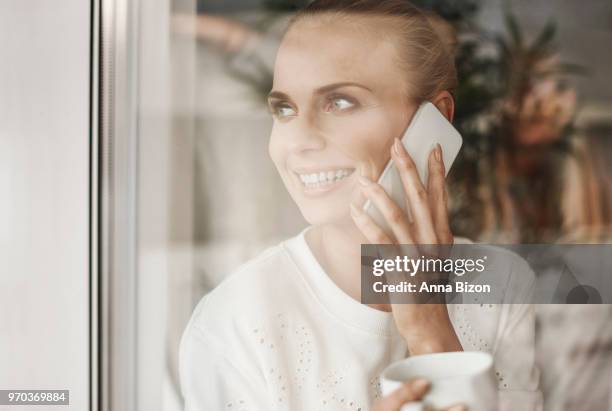 happy businesswoman looking through window and talking on mobile phone. debica, poland - happy mobile stockfoto's en -beelden