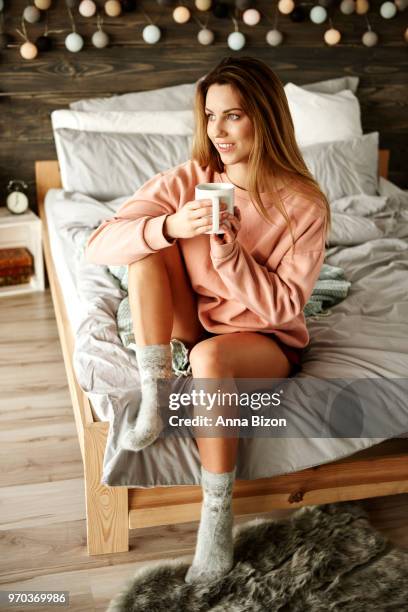 portrait of woman with coffee sitting on bed. debica, poland - lazy poland stock pictures, royalty-free photos & images