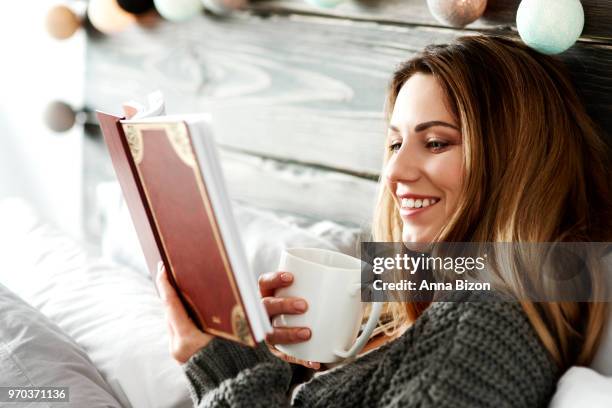 woman with coffee reading book in bedroom. debica, poland - lazy poland fotografías e imágenes de stock