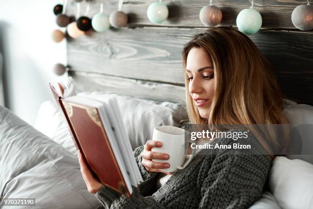 woman drinking coffee and reading book on bed. debica, poland - lazy poland fotografías e imágenes de stock