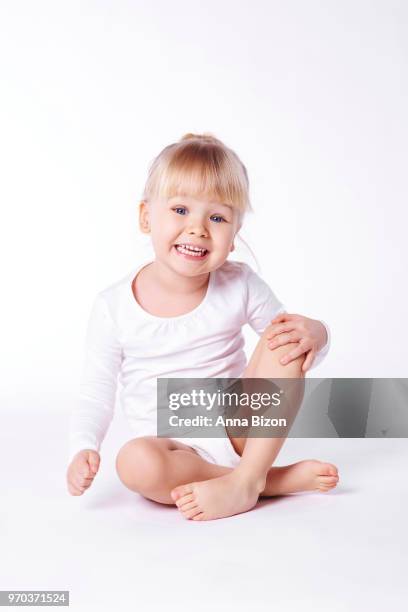 toddler sitting in white top with thick fringe, smiling at camera, studio shot. debica, poland - thick girls stock-fotos und bilder