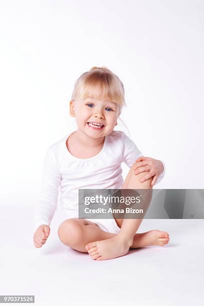 toddler sitting in white top with thick fringe, smiling at camera, studio shot. debica, poland - thick girls stockfoto's en -beelden