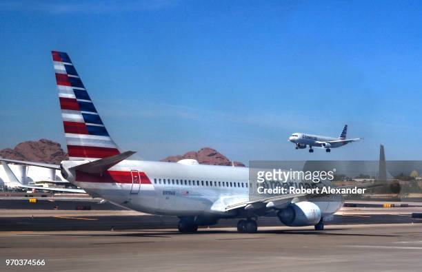 An American Airlines commercial jet takes off as another taxis to its gate at Phoenix Sky Harbor International Airport in Phoenix, Arizona.