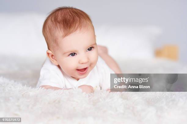 cheerful baby lying on its front on fury white blanket. debica, poland - baby girl laying on tummy stock pictures, royalty-free photos & images