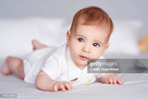 baby lying on tummy on bed. debica, poland - baby girl laying on tummy stock pictures, royalty-free photos & images