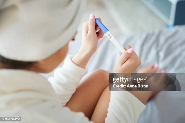 woman looking at pregnancy test showing positive results. debica, poland - anna bizon stock pictures, royalty-free photos & images