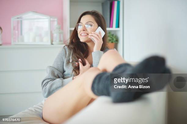 woman relaxing on couch with legs up while talking on phone. debica, poland - anna bizon stock pictures, royalty-free photos & images