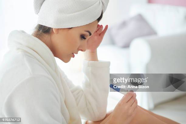 woman looking with concerned expression at pregnancy test. debica, poland - anna bizon stock pictures, royalty-free photos & images
