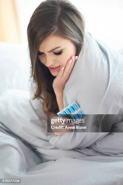 young woman holding sachet of tablets lying in bed. debica, poland - anna bizon foto e immagini stock