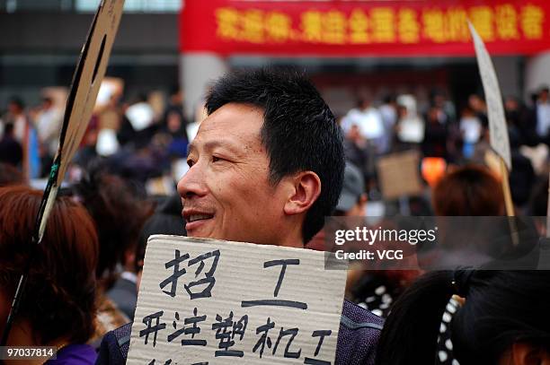 Recruiter lifts his pasteboard showing job offers to attract job hunters on February 24, 2010 in Yiwu, Zhejiang province of China. Increasing...