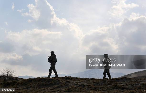 In this February 23, 2010 photograph, US soldiers with the 4th Infantry Division, 4th Infantry Brigade Combat Team, Alpha Company, scale a hill while...