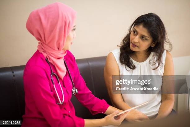 female muslim doctor consulting with a patient - gp visit stock pictures, royalty-free photos & images