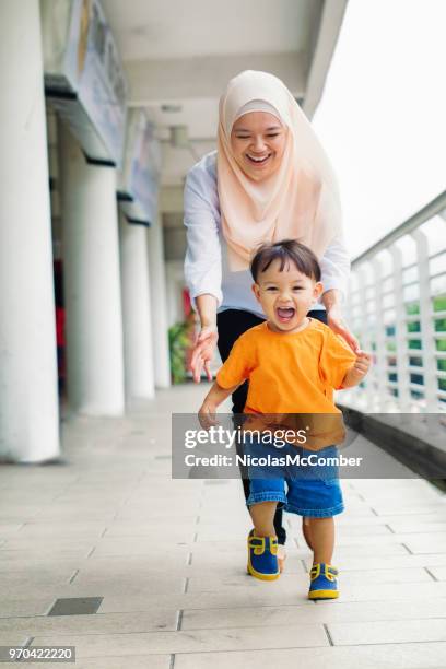 muslimsk mor skrattar bakom kör ung son - asian young family bildbanksfoton och bilder