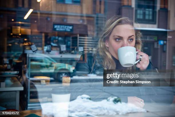 woman with coffee cup in window of cafe - bakery window stock pictures, royalty-free photos & images