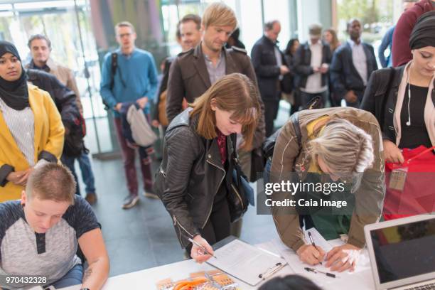 Business people arriving, checking in at conference registration table