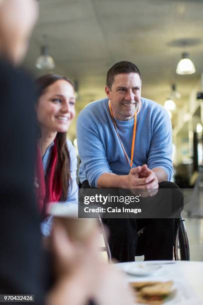 Smiling businessman in wheelchair networking, talking with colleagues