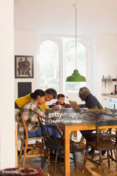 grandparents helping grandchildren with homework at dining table - couple in kitchen stock pictures, royalty-free photos & images