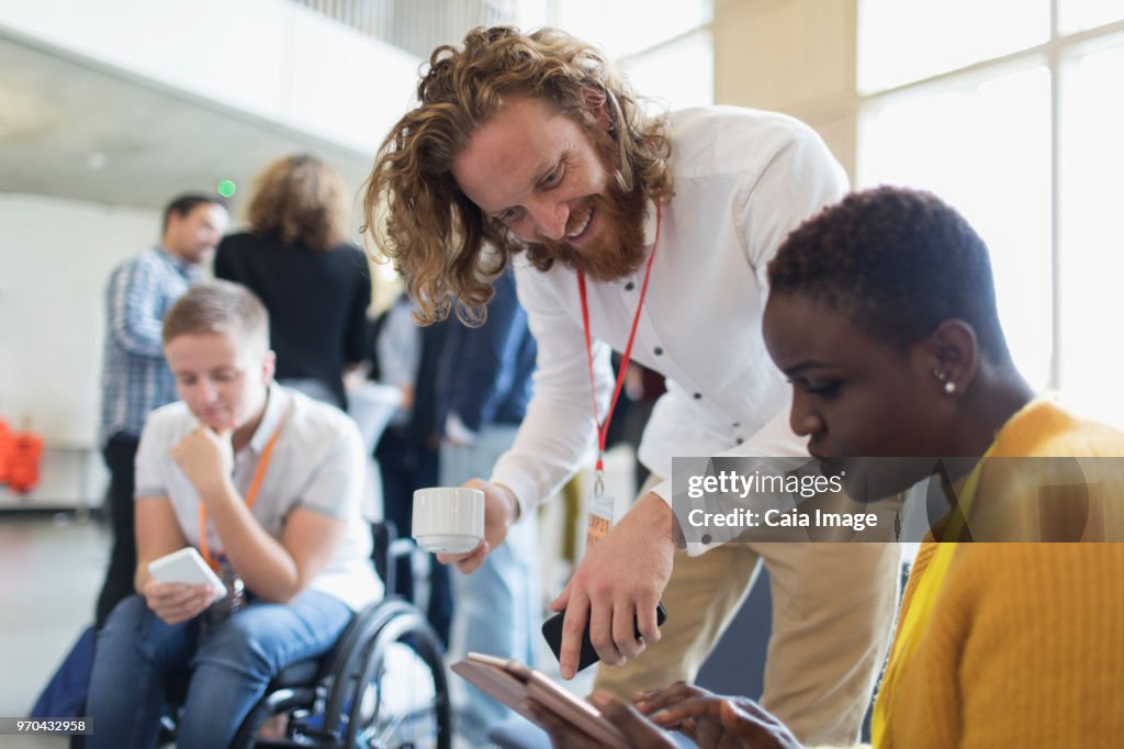 Business people drinking coffee and using digital tablet at conference