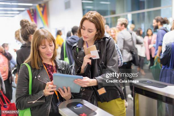 Women with digital tablet at turnstile