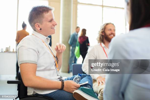 Smiling woman in wheelchair talking to colleagues at conference