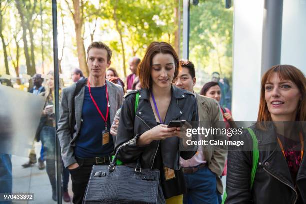 Businesswoman with smart phone arriving, entering doorway