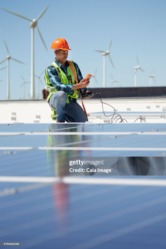 Engineer with equipment inspecting solar panels at sunny power plant
