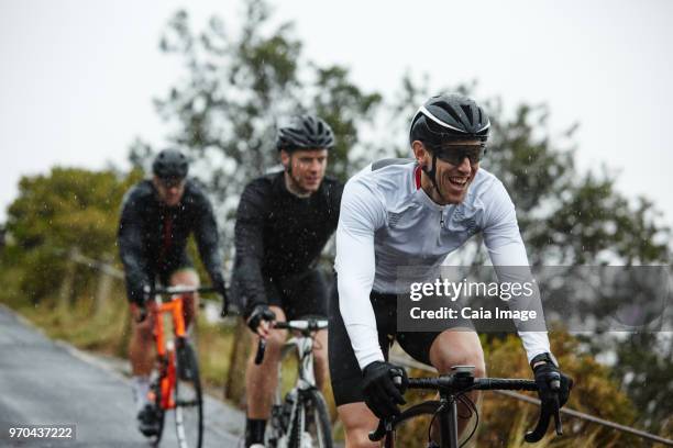 smiling male cyclist cycling with friends - men's cycling stock pictures, royalty-free photos & images